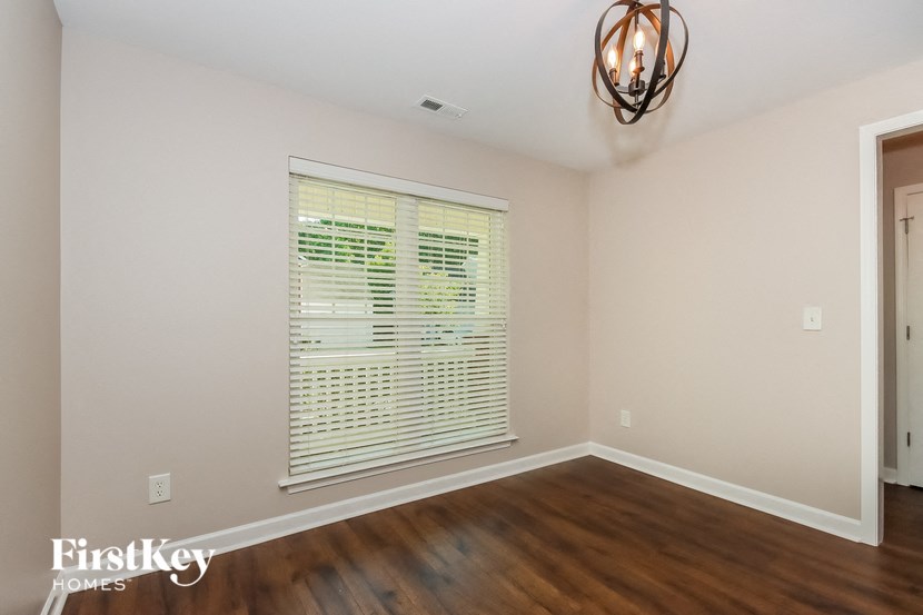 a living room with wood floors and a large window with blinds