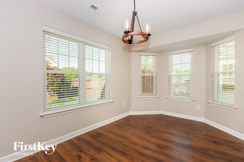 a living room with wood floors and windows and a chandelier