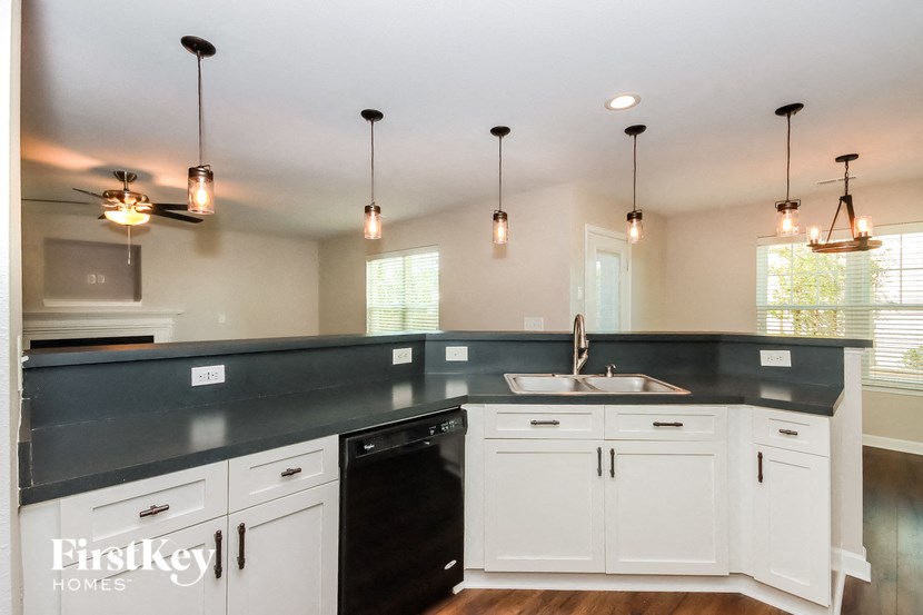 a kitchen with white cabinets and black counter tops and lights