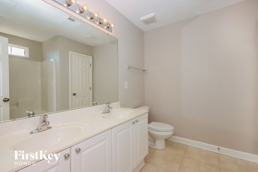 a bathroom with a large mirror and a white sink and toilet
