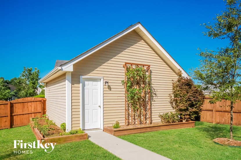 a small tan house with a white door and a backyard