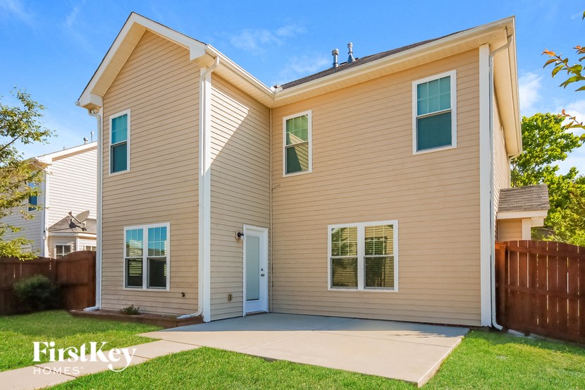a beige house with a white door and a driveway