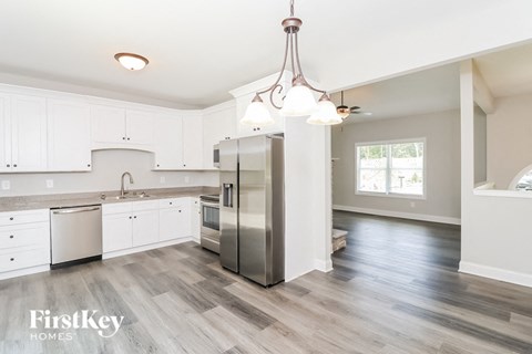 A modern kitchen with a stainless steel refrigerator and wooden flooring.