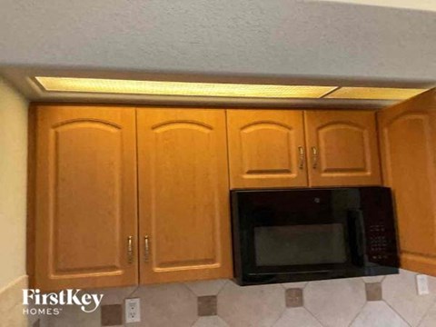 A black microwave oven is installed in a kitchen cabinet.