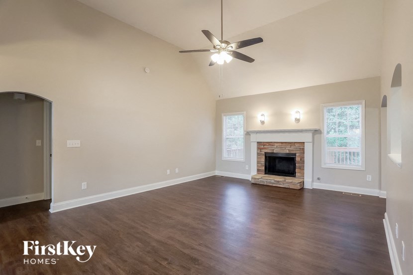 A spacious living room with a fireplace and a ceiling fan.