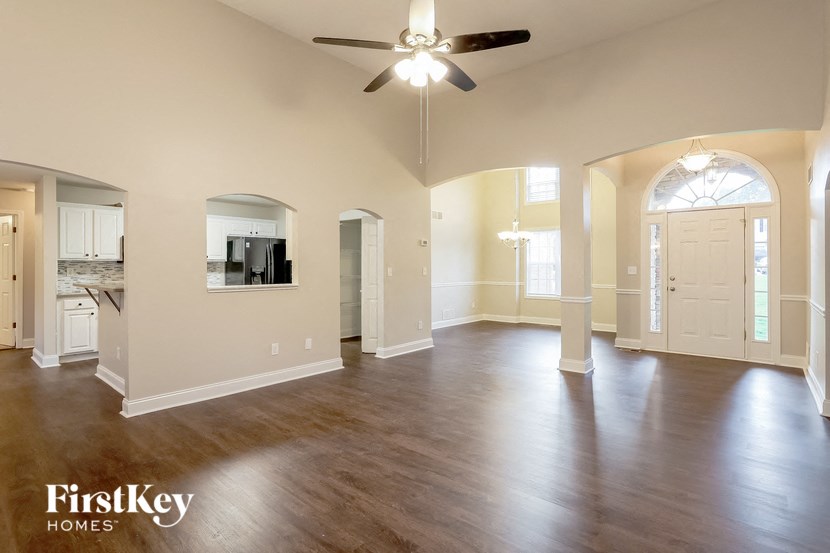 A spacious living room with a ceiling fan and hardwood floors.