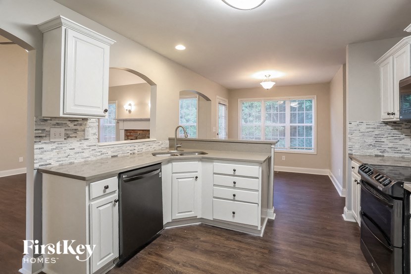 A kitchen with white cabinets and a stone backsplash.