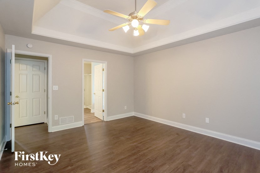A room with a ceiling fan and wooden floors.