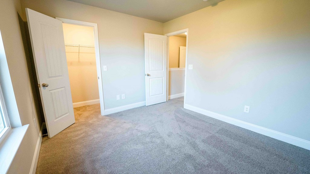 an empty bedroom with white walls and carpet
