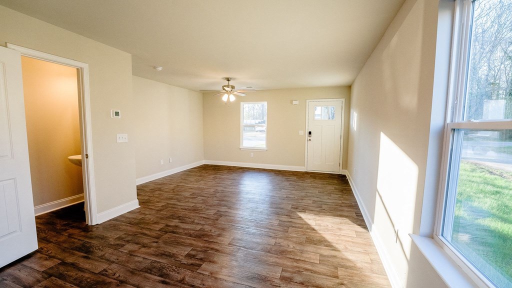 an empty living room with a wood floor and a ceiling fan