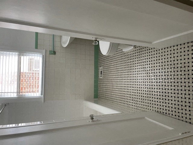 A bathroom with a white tub and green and white tiles.