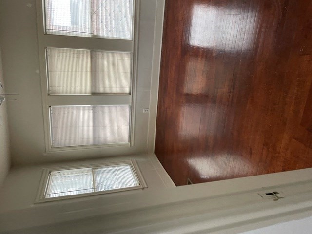 A window with a white frame is in a room with wooden walls.