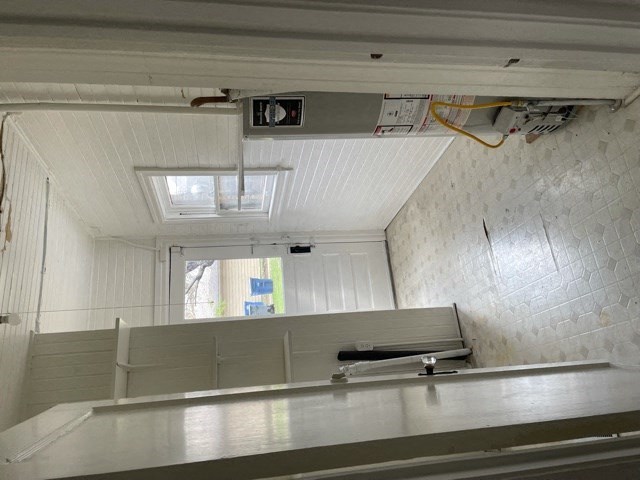 A white ceiling with a skylight and a white wall with a window.