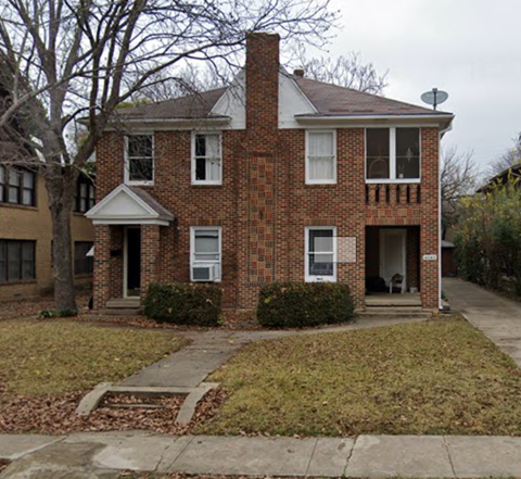 a brick house with a sidewalk in front of it