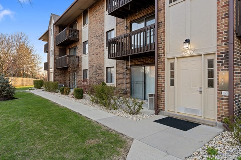 Apartment building with balconies and doors on the ground floor.