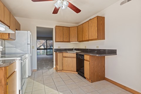 A kitchen with a black counter top and wooden cabinets.