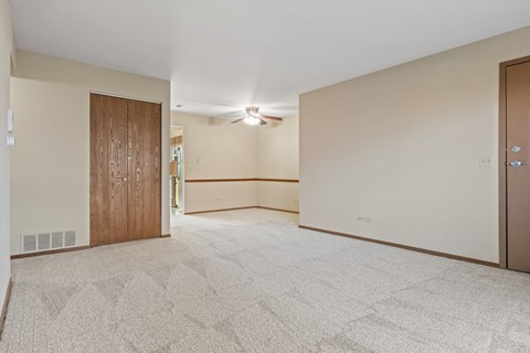 A spacious room with a carpeted floor and a ceiling fan.
