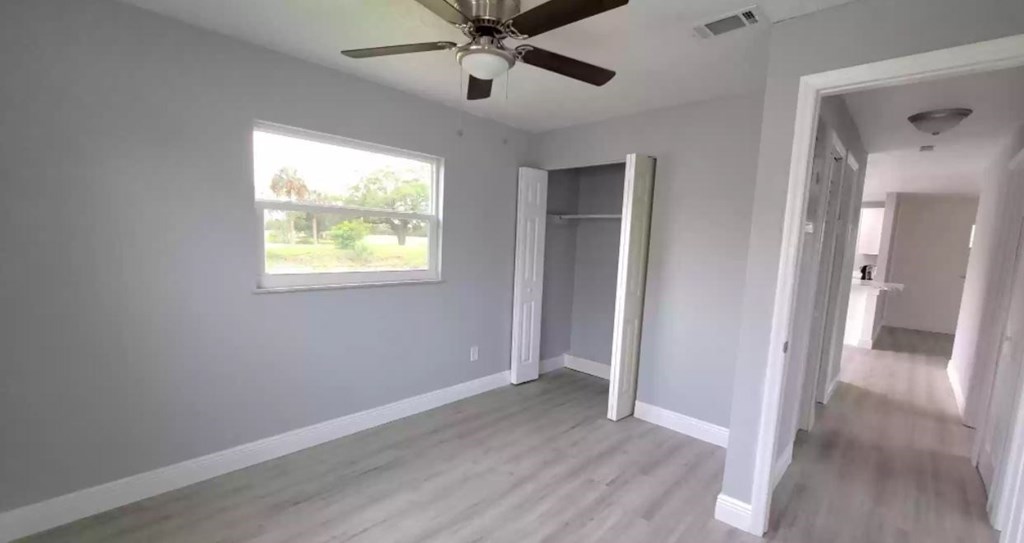 an empty living room with a ceiling fan and a window