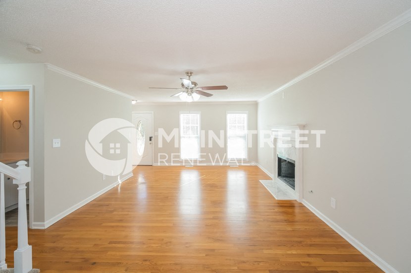 a large living room with a wood floor and a ceiling fan