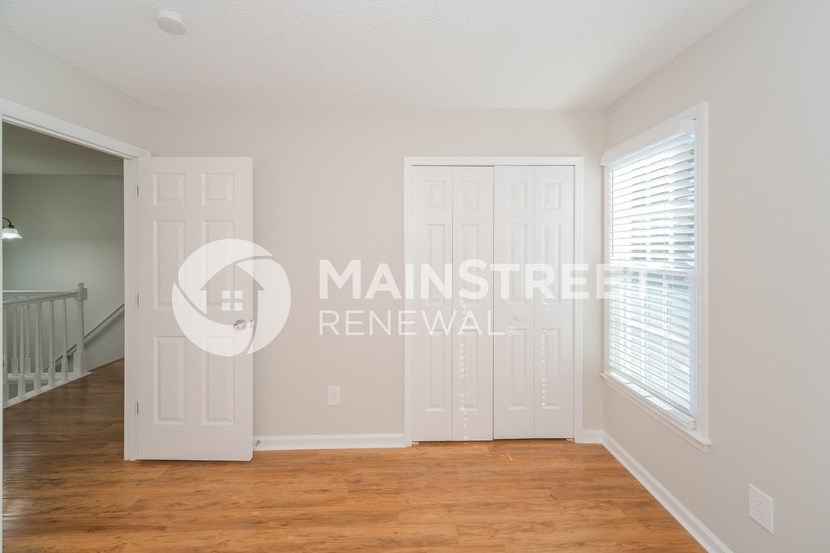 a renovated living room with two doors and a wood floor