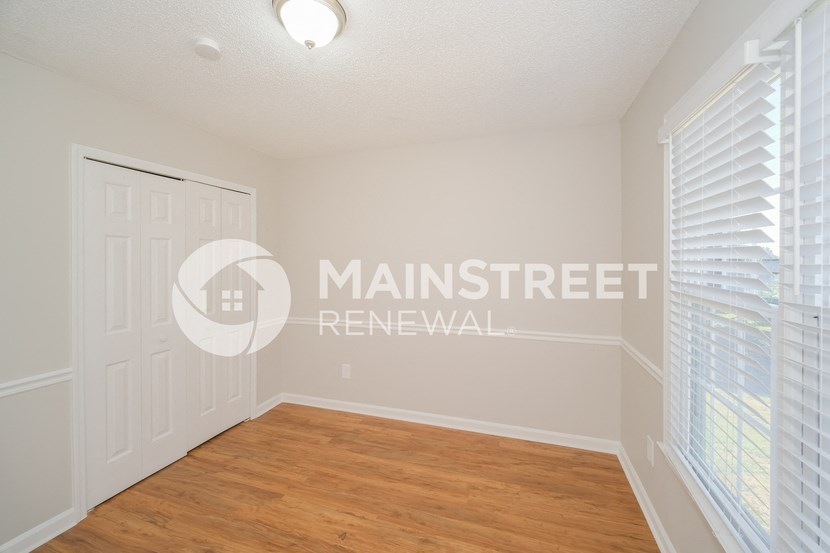 a bedroom with a wood floor and a white door