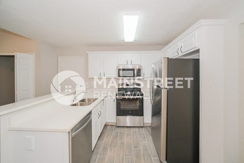 a renovated kitchen with white cabinets and stainless steel appliances