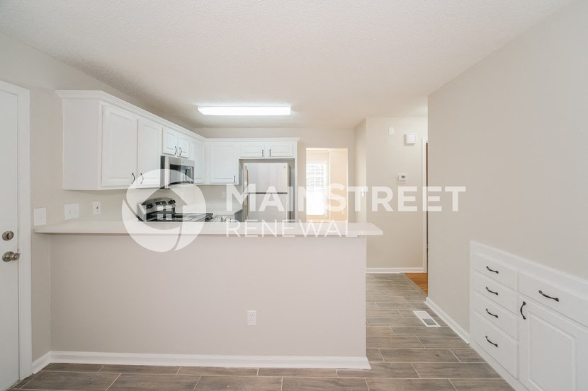 a renovated kitchen with white cabinets and a counter