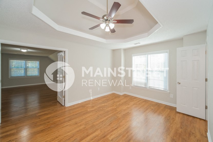 a renovated living room with hardwood floors and a ceiling fan