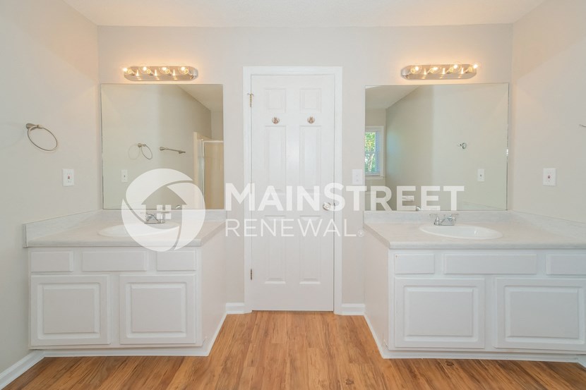 a renovated bathroom with white cabinets and a large vanity with two sinks