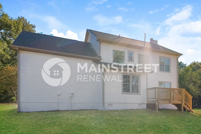 a white house with a deck and a grass yard