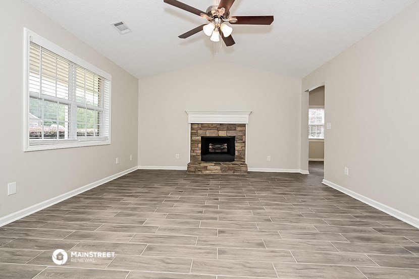 an empty living room with a fireplace and a ceiling fan