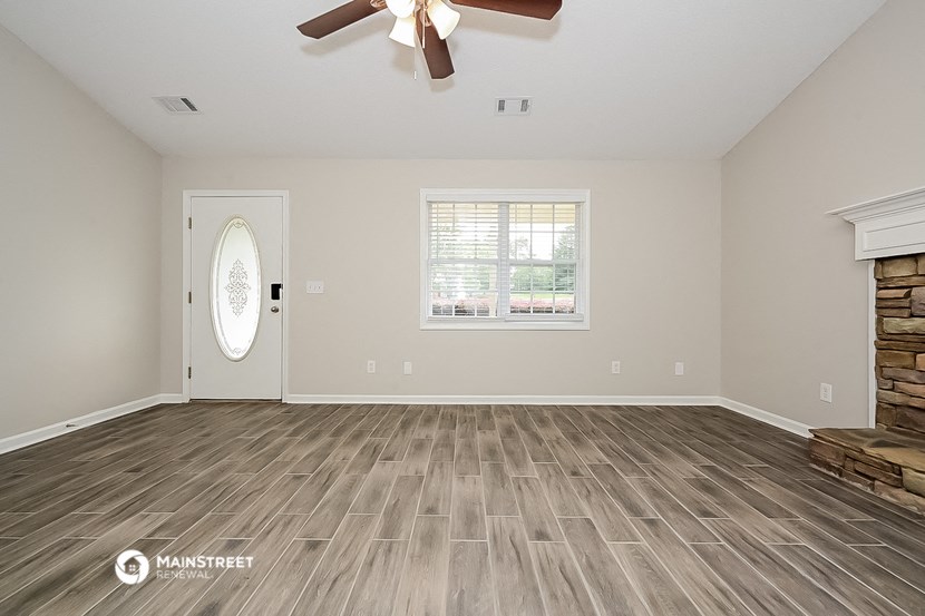 an empty living room with a ceiling fan and a window