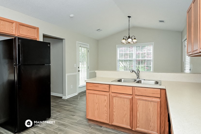 an empty kitchen with a black refrigerator and a sink