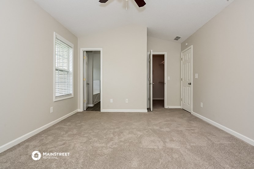 an empty living room with a large window and a ceiling fan