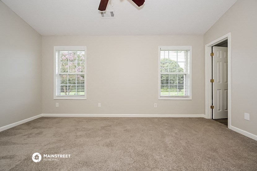 an empty room with a door and two windows