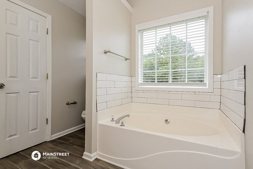 a white bathroom with a tub and a window
