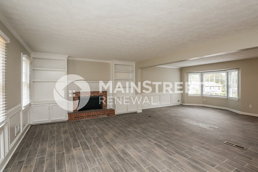 an empty living room with a fireplace and wood floors