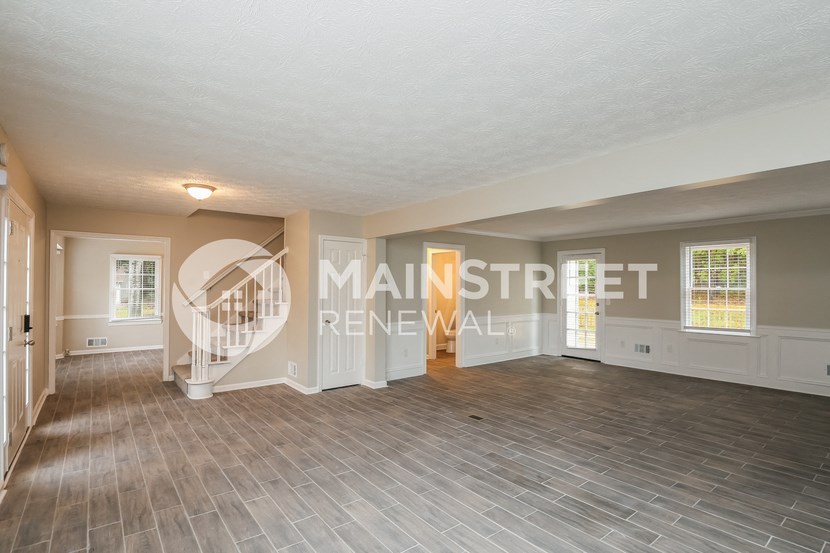 a living room with a staircase and a hard wood floor