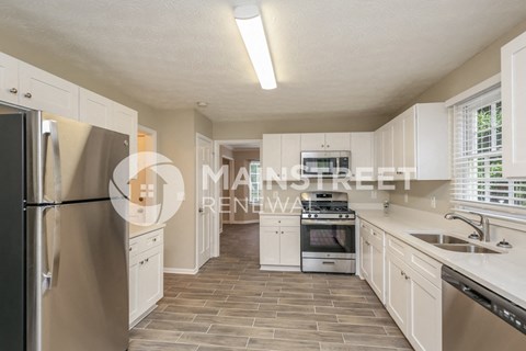 a renovated kitchen with white cabinets and stainless steel appliances