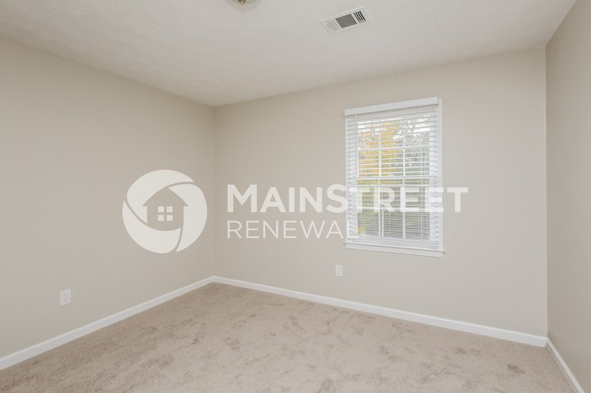 a bedroom with a large window and beige carpet