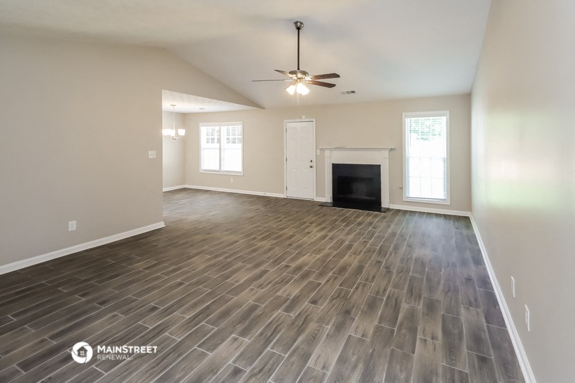 the living room of an empty house with a fireplace and a ceiling fan
