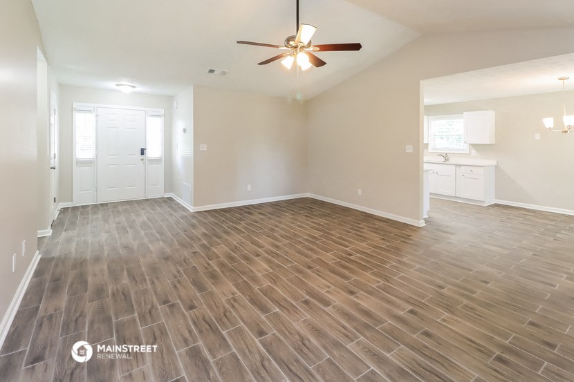 the spacious living room with wood flooring and a ceiling fan