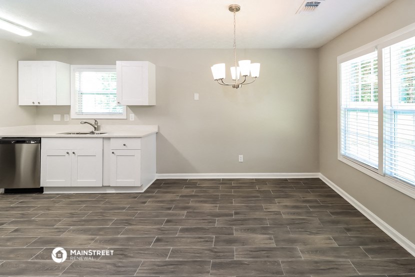 an empty kitchen with white cabinets and a sink and a window
