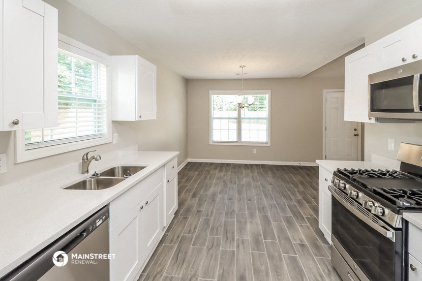 an empty kitchen with white cabinets and stainless steel appliances
