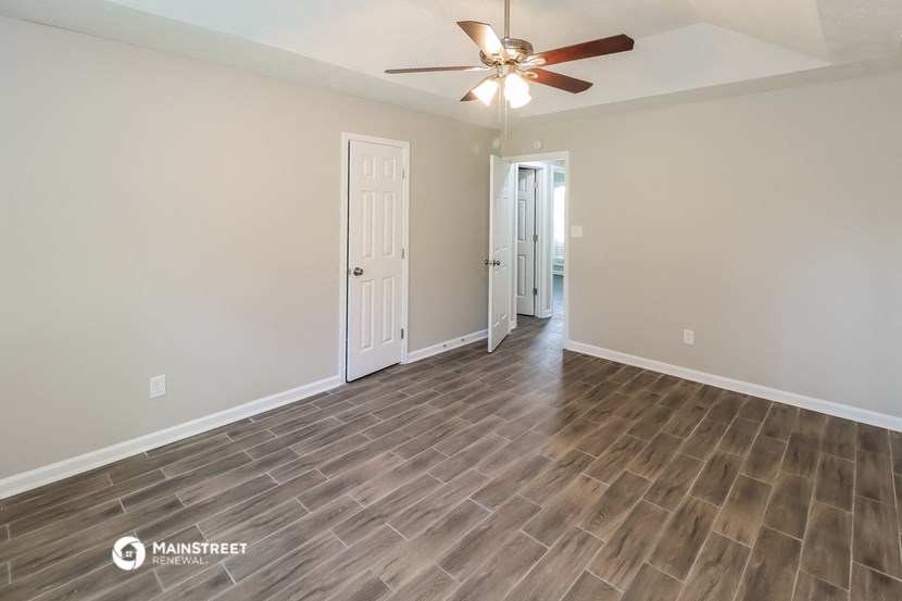 the spacious living room with wood flooring and a ceiling fan