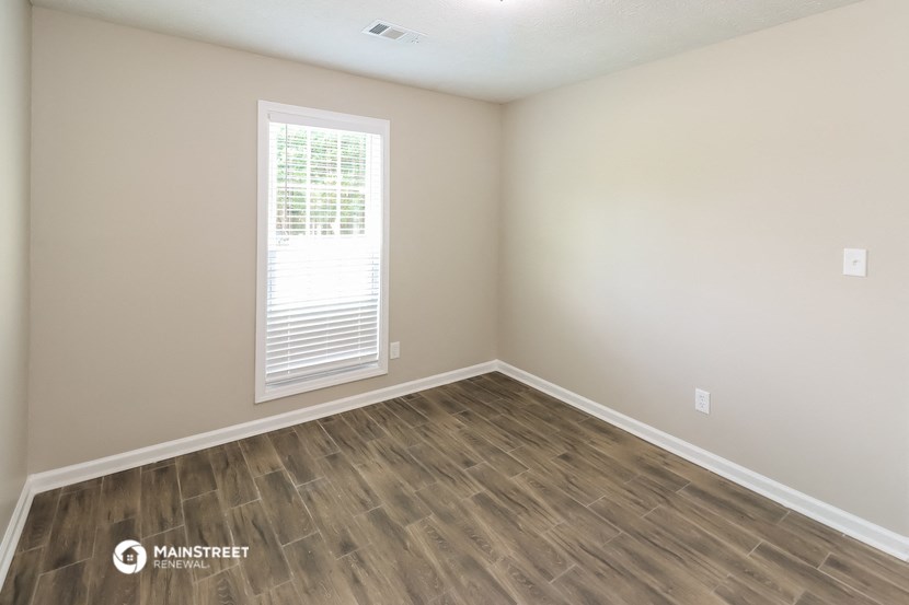 the interior of an empty room with wood floors and a window