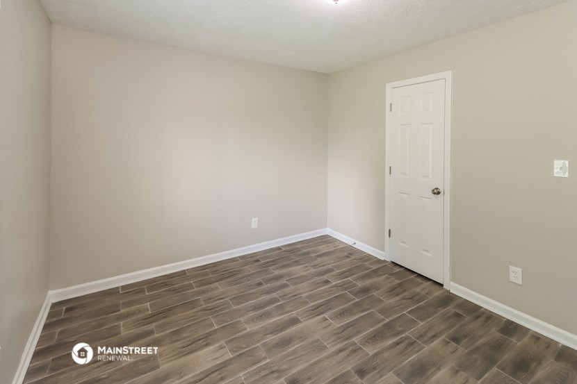 the spacious living room with wood flooring and a white door