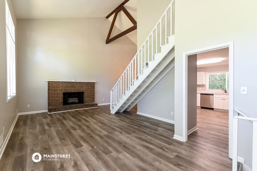 an empty living room with a fireplace and a staircase