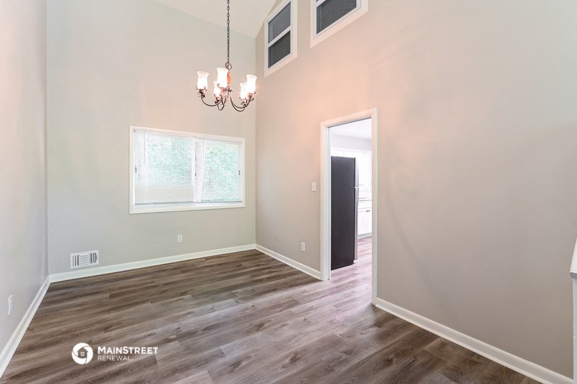 the spacious living room with hardwood flooring and white walls