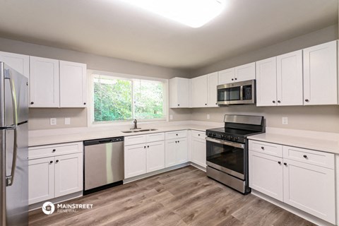 the kitchen of an apartment with white cabinets and stainless steel appliances